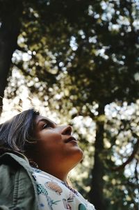 Low angle view of woman looking up against trees