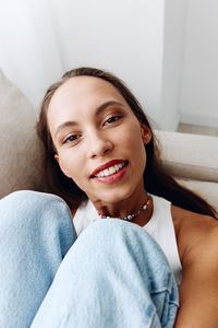 Portrait of young woman lying on bed at home