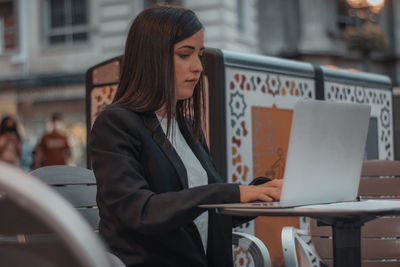 Young businesswoman using laptop at cafe