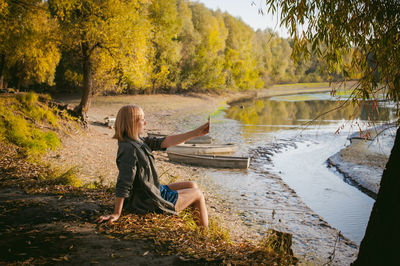 Young woman sitting on lake in forest