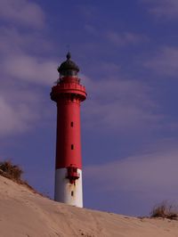 Lighthouse on beach against sky