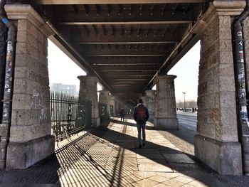 Rear view of man walking under bridge
