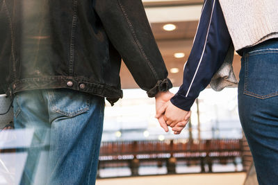 Midsection of young couple holding hands while standing at subway station