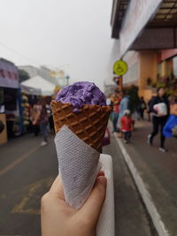 Midsection of person holding ice cream in city