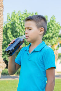 A young boy drinks soda from a plastic bottle. vertical shot.