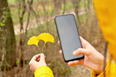 Midsection of woman photographing flower