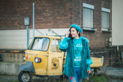 Portrait of smiling young woman standing against brick wall