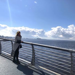 Full length of woman standing by railing on pier over sea against sky