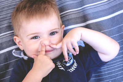 High angle portrait of cute boy lying on bed