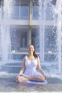 Portrait of woman sitting against waterfall