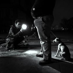 Low section of man playing with dog at night