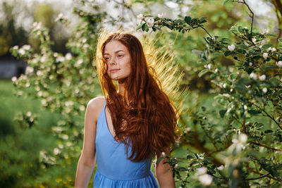 Portrait of young woman standing against plants