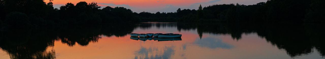 Panoramic shot of rowing boats on a lake with reflections and contrasting sky