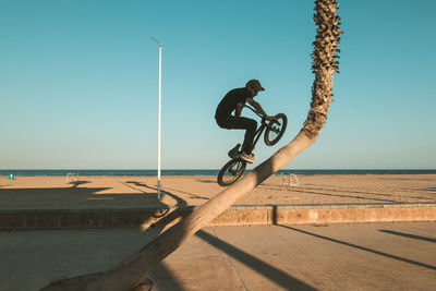 Man performing stunt with bicycle against clear sky