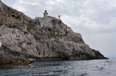 Rock formations by sea against sky