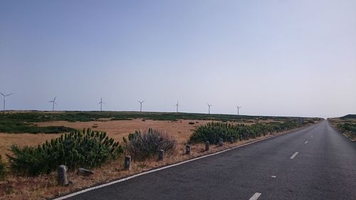 Road by field against clear sky
