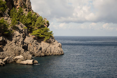 Rock formation by sea against sky