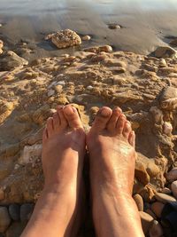 Low section of woman on sand at beach during sunset