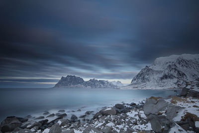 Scenic view of sea and snowcapped mountains against sky during winter