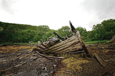 Abandoned wooden structure on field against sky