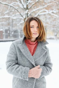 Portrait of young woman standing on snow covered field