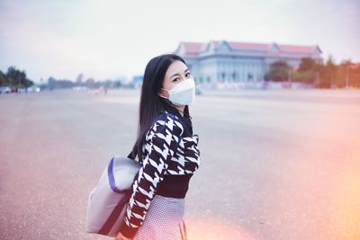 Portrait of young woman standing against sky