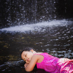 Cute girl lying against waterfall