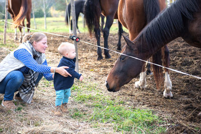 Mother and son looking at horses in ranch