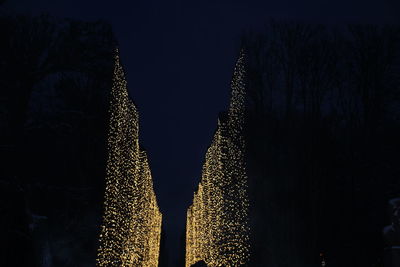 Low angle view of illuminated christmas lights against sky at night