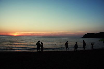 Silhouette people on beach at sunset