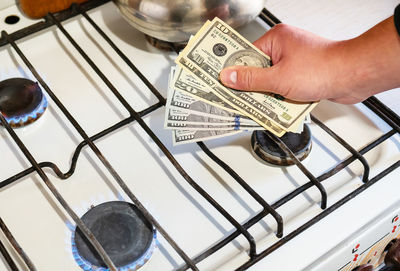 Payment of utility services. dollar bills are held in their hands near a burning gas burner. 