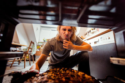 Full length of man sitting in kitchen