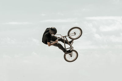 Man performing stunt with bicycle against sky