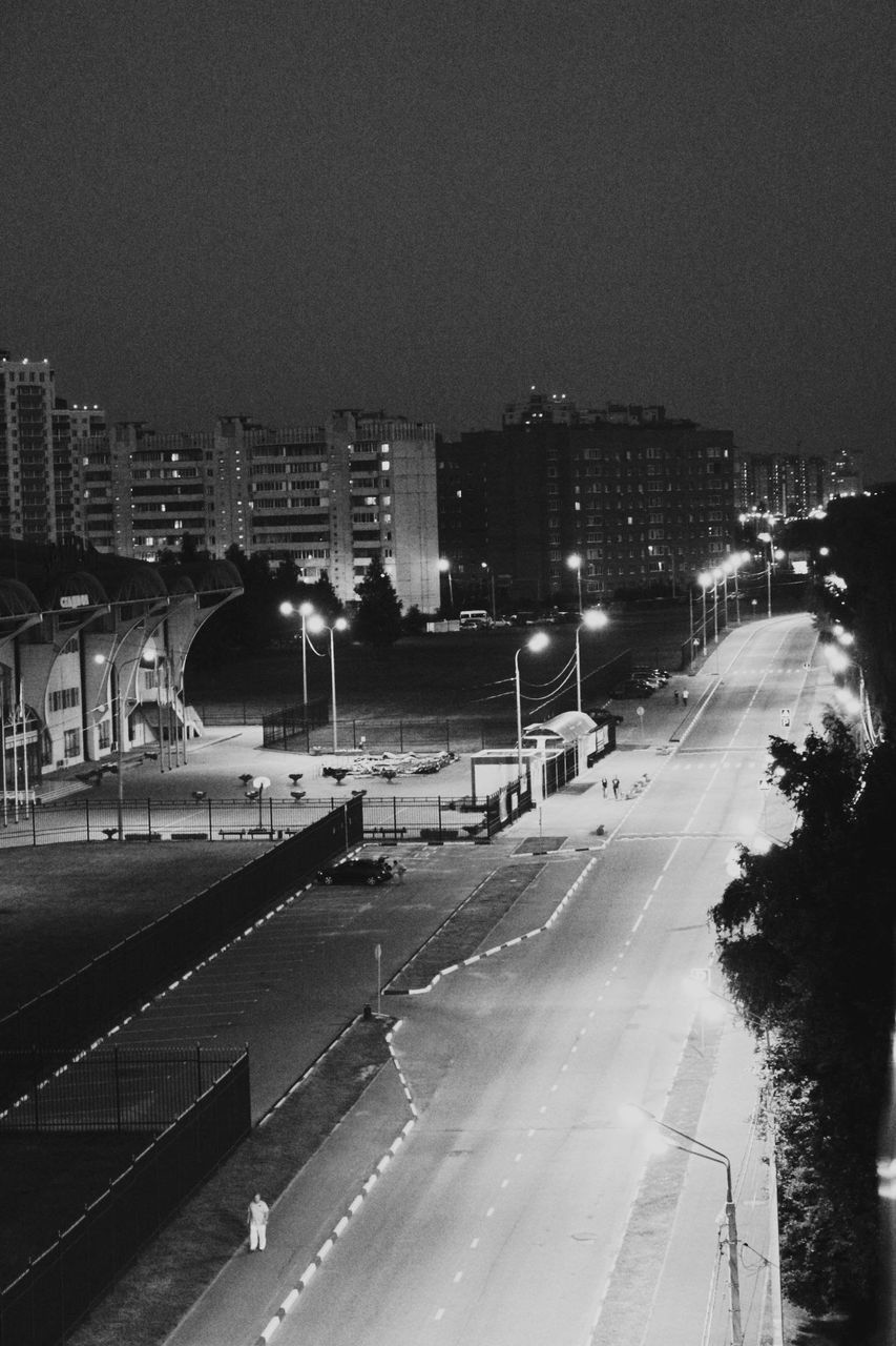 building exterior, architecture, city, built structure, night, cityscape, illuminated, clear sky, high angle view, road, transportation, city life, street, copy space, road marking, street light, outdoors, sky, residential building, city street