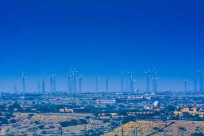 Wind turbines in city against clear blue sky