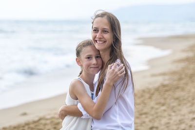 Portrait of mother with daughter standing at beach