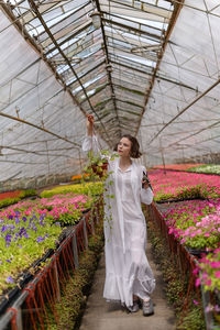 Rear view of young woman standing in greenhouse