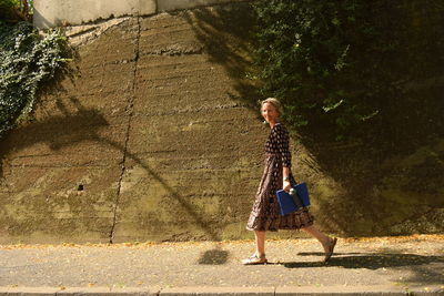 Woman with umbrella walking on footpath