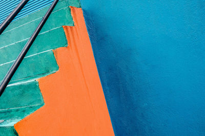 Abstract shot of green steps at painted blue and orange wall