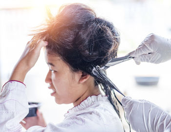 Hairdresser applies a hair mask to the woman in the beauty salon. 