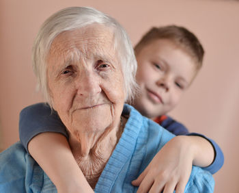 Lovely little boy with his grandmother wearing a blue jacket at home having fun 