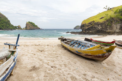 Boat moored on beach against sky