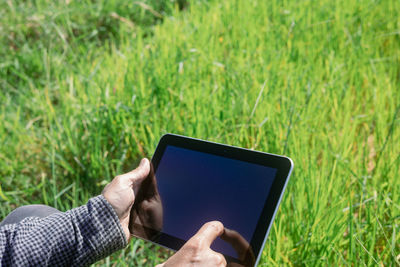 Midsection of man using mobile phone in field