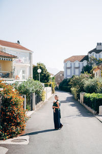 Woman standing by building against sky in city