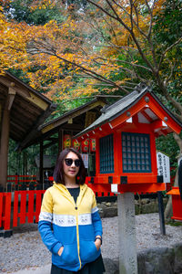 Portrait of young woman standing against trees