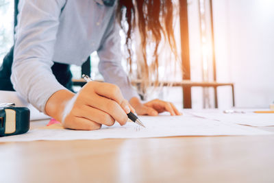 Midsection of woman holding umbrella on table