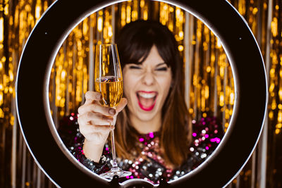 Cheerful young woman with champagne against decorations