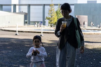 Mother and daughter having drinks while standing on road