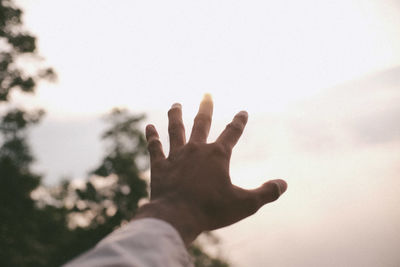 Close-up of hand against sky