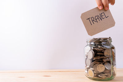 Close-up of hand holding coin against white background